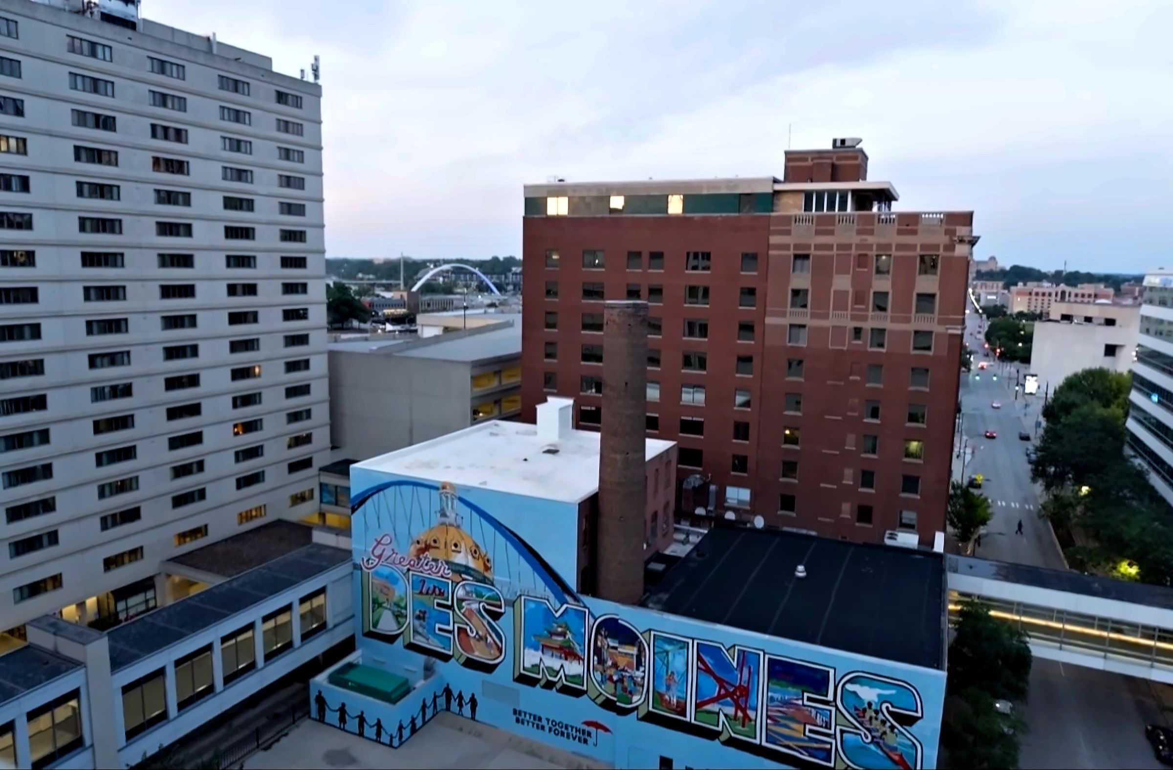 A Greetings from Des Moines mural painted on a building downtown at dusk